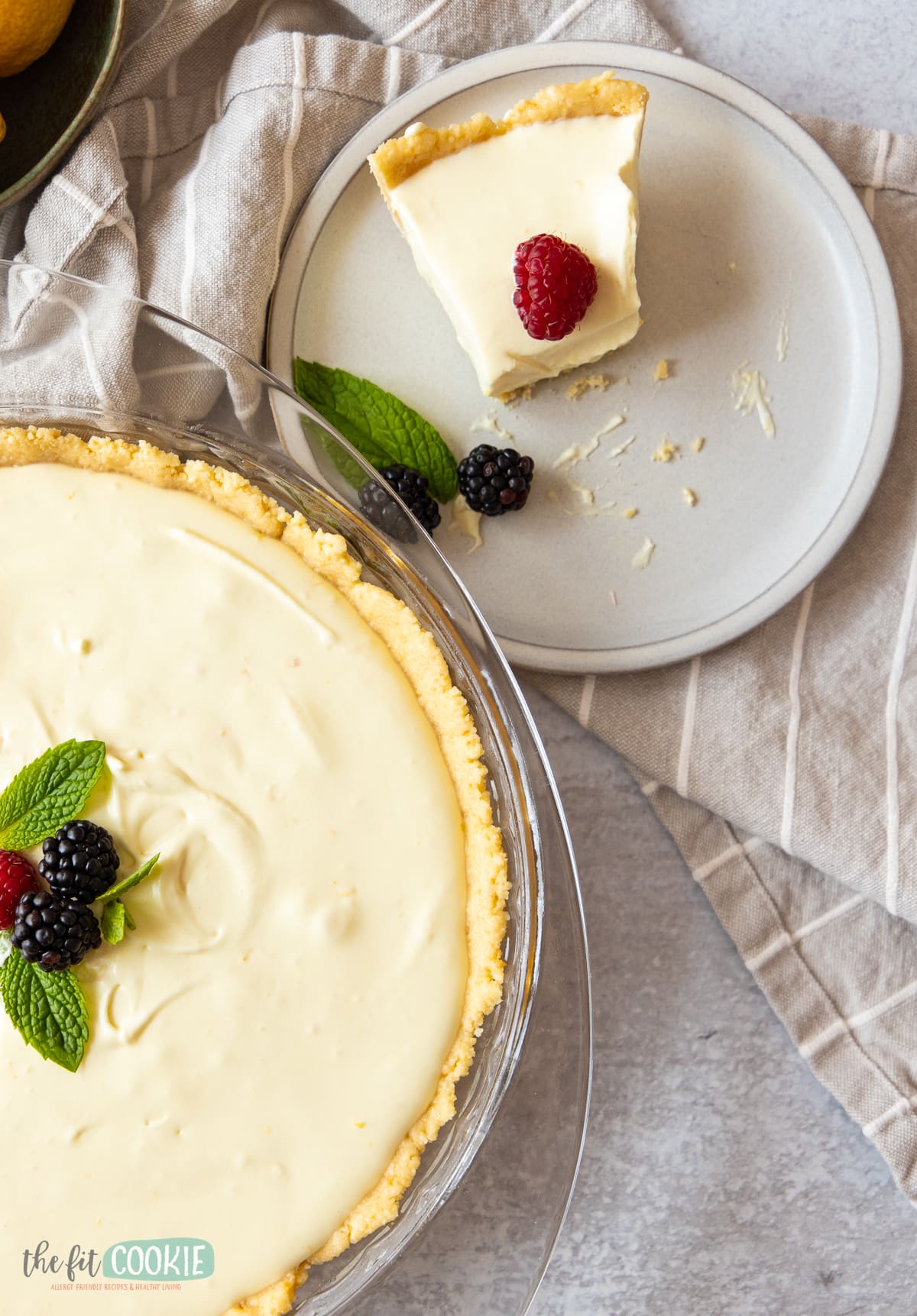 overhead photo of dairy free lemon cheesecake in a glass dish with berries on top. 