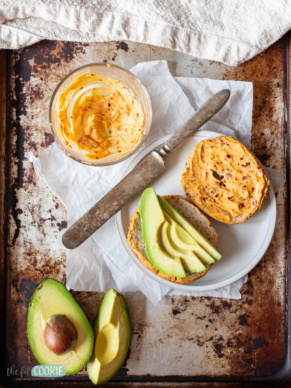 overhead photo of bagel with chili mayo on it and avocado slices. 