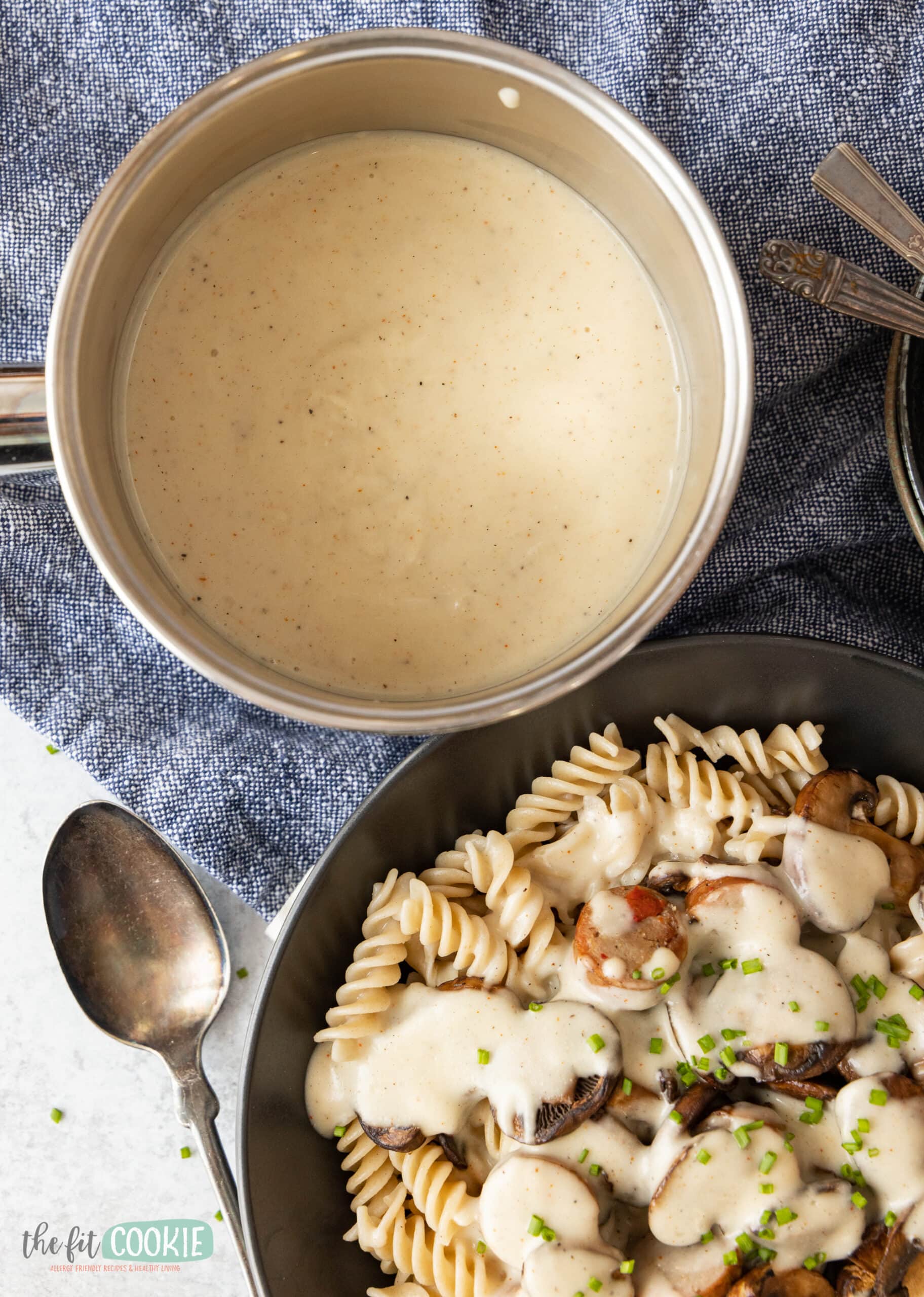 overhead photo of alfredo sauce in a pan next to a dish of pasta alfredo. 