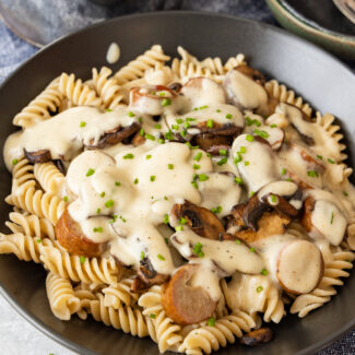 A bowl of alfredo pasta with mushroom sauce and parmesan cheese.