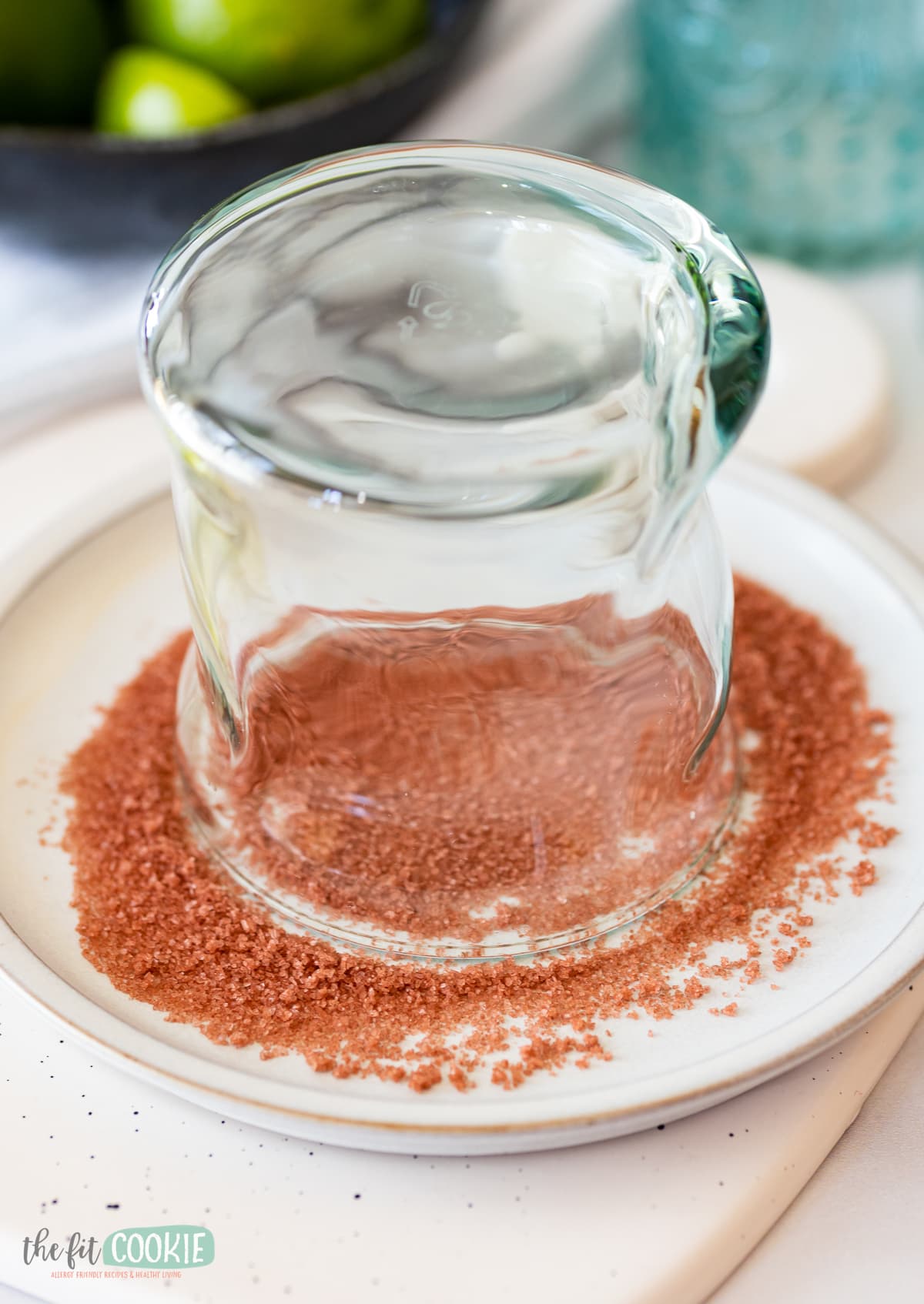 glass being added to red salt on a white plate for a salt rimmed glass. 