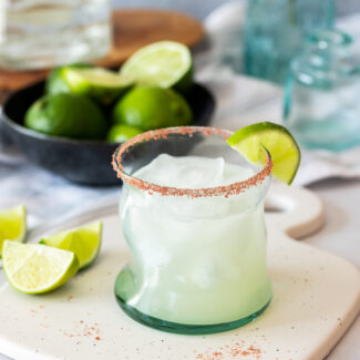 A soursop margarita with lime and salt on a cutting board.