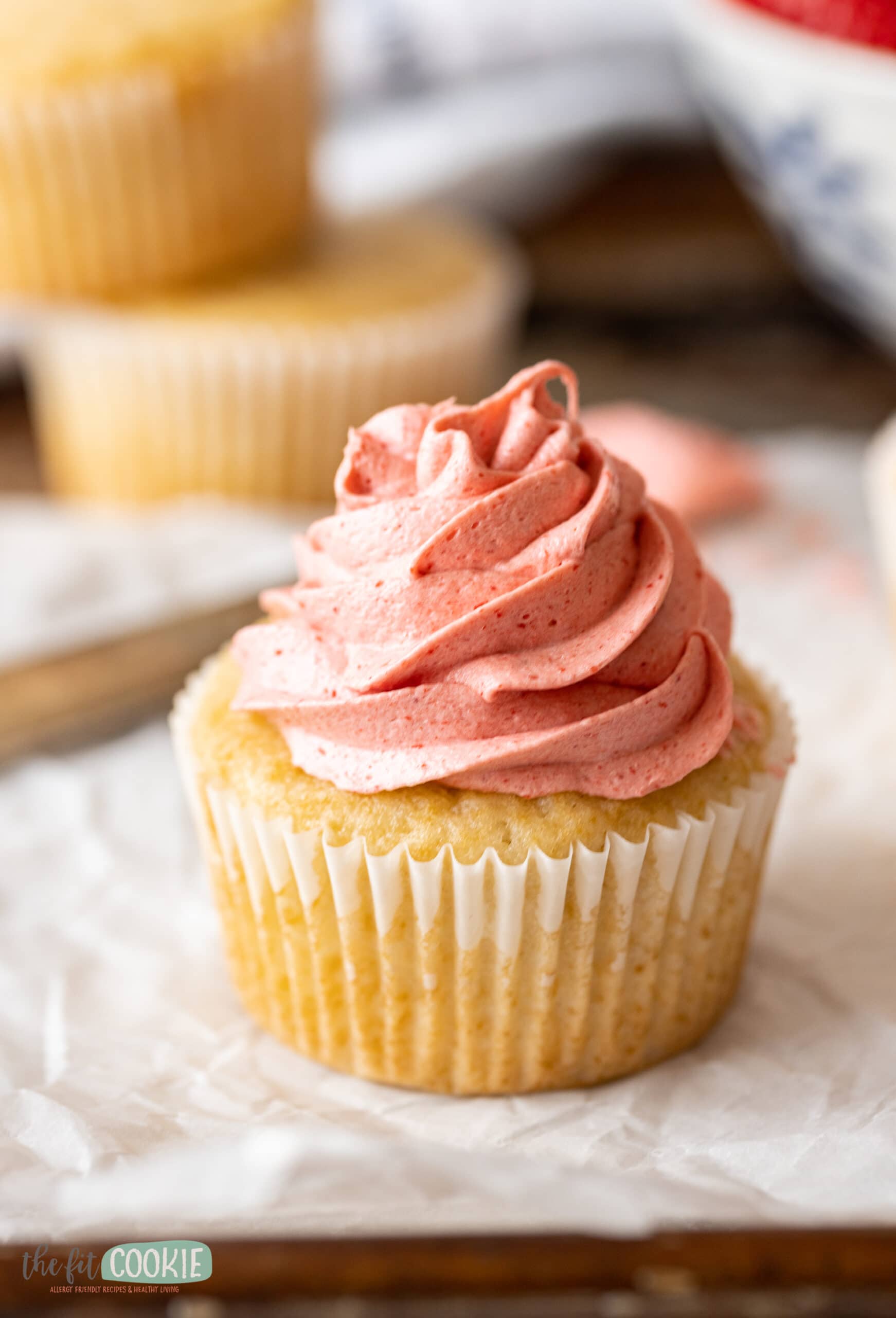 close up photo of a cupcake topped with piped strawberry buttercream. 