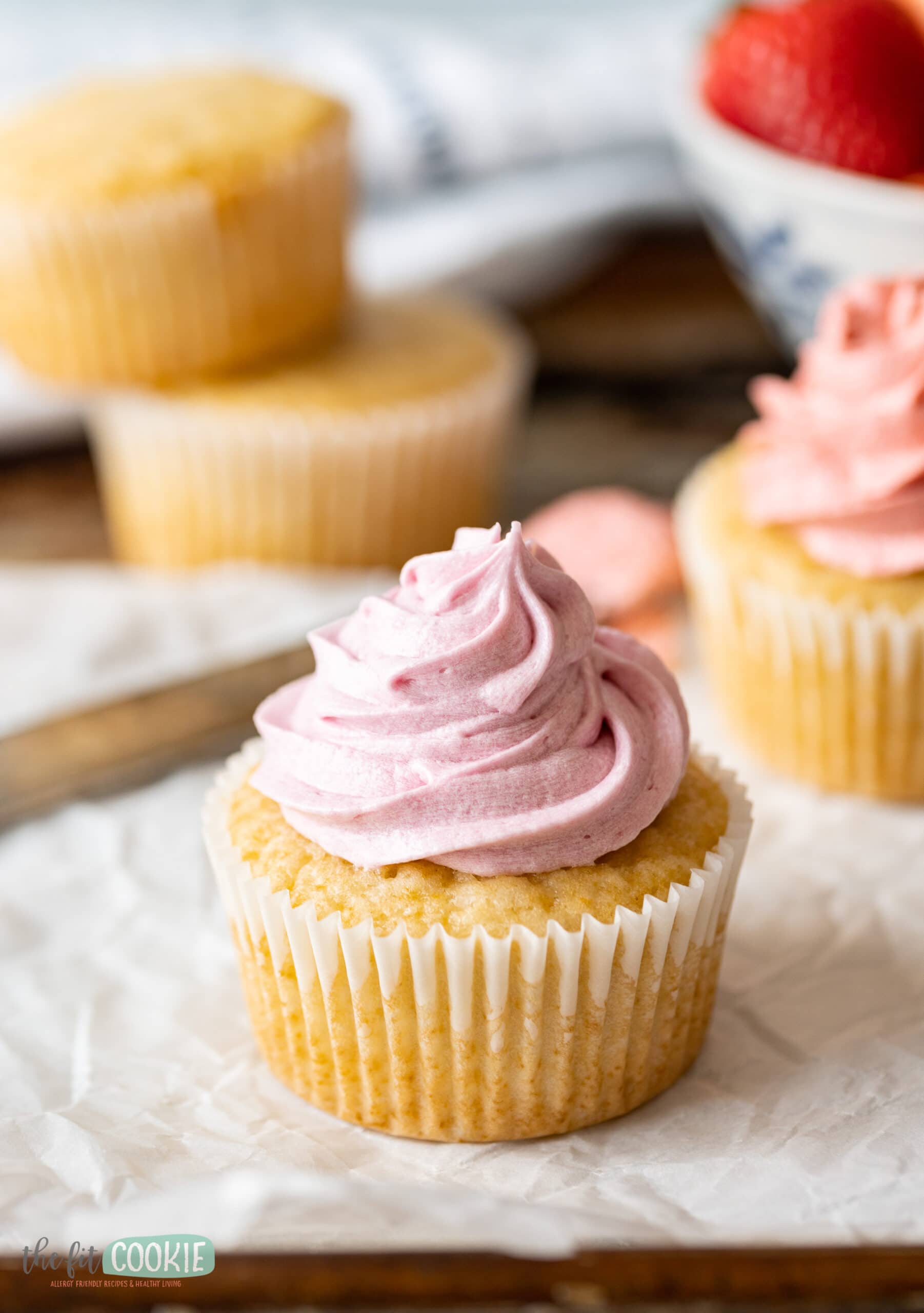 close up photo of pinkish purple colored strawberry frosting on a vanilla cupcake. 
