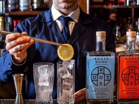 A bartender pouring gin into a glass.