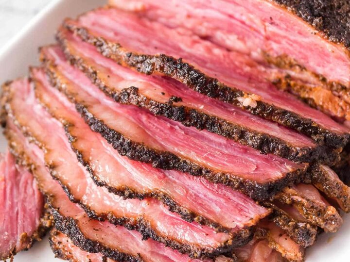 A sliced piece of brisket on a white plate.