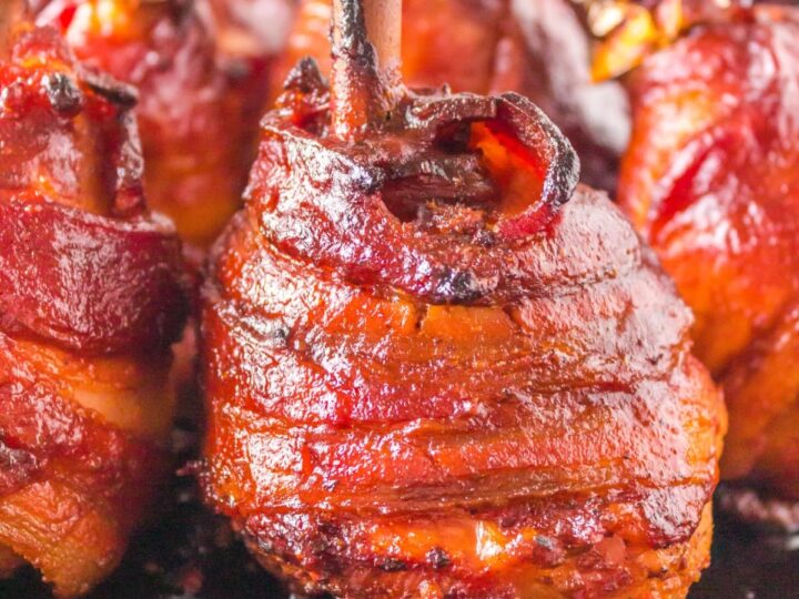 Bacon wrapped skewers on a black plate.