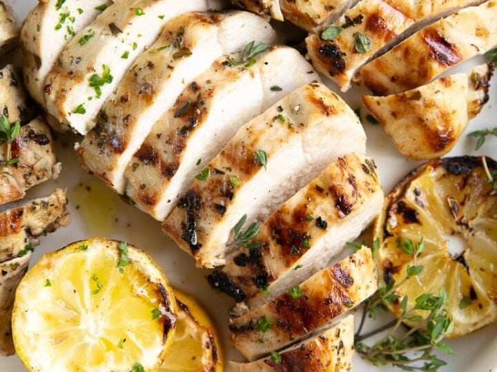 Grilled chicken with lemon slices on a plate.