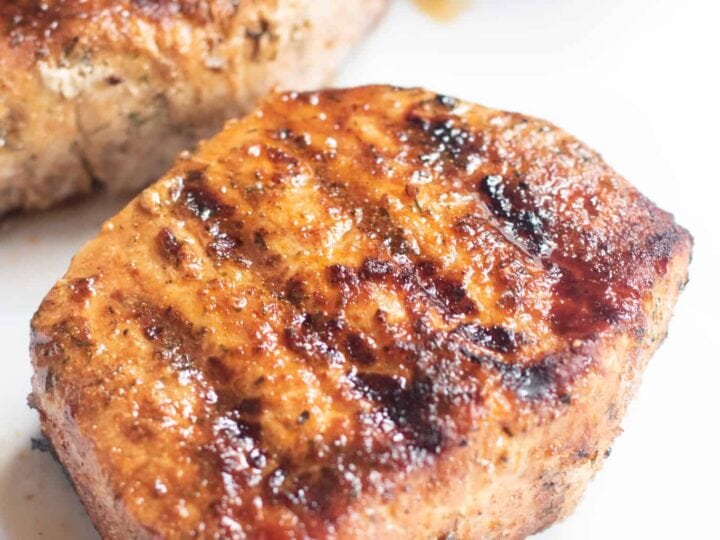 Grilled pork chops on a white plate.