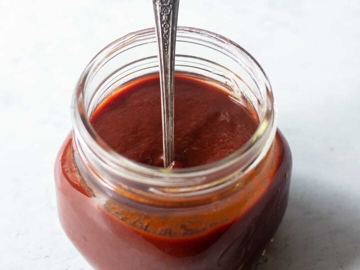 A jar of red sauce with a spoon.