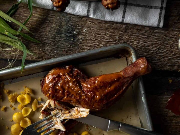A tray of chicken and corn on a table with a fork.