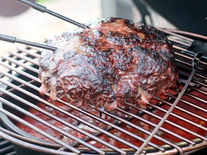 A piece of meat is being cooked on a grill.