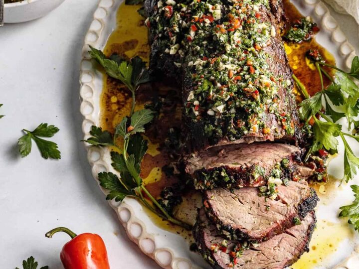 A roasted lamb with herbs and spices on a plate.