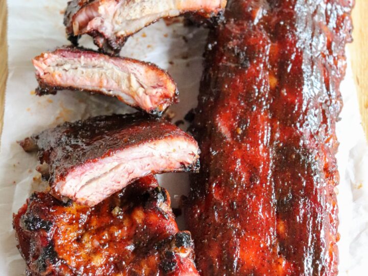 Bbq ribs on a cutting board with sauce.