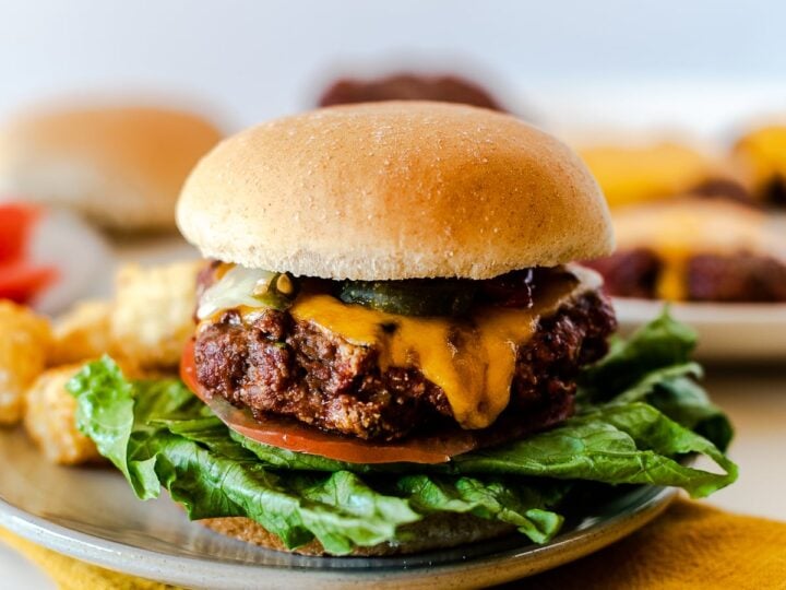 A burger with cheese and lettuce on a plate.