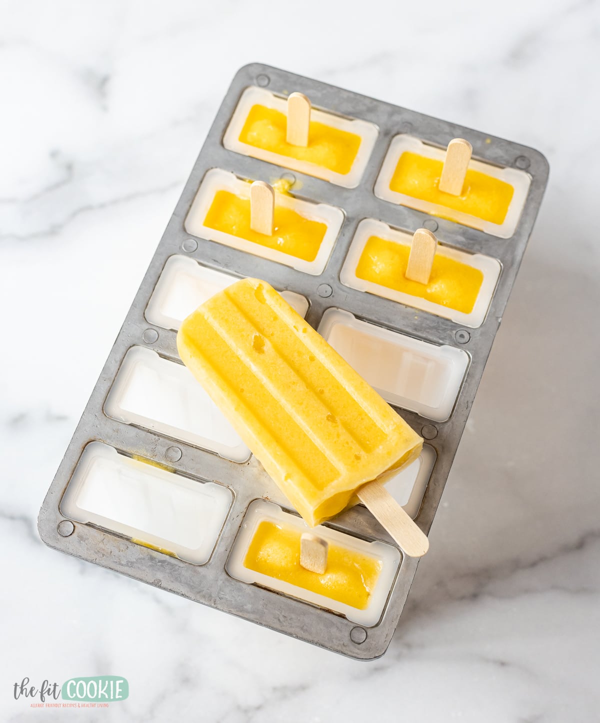 photo of mango popsicle on a metal and plastic popsicle mold.