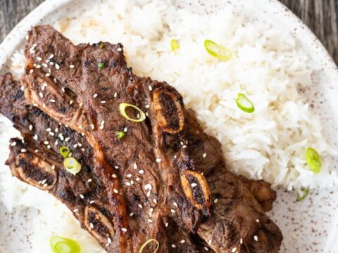 Korean ribs on a plate with rice and sesame seeds.