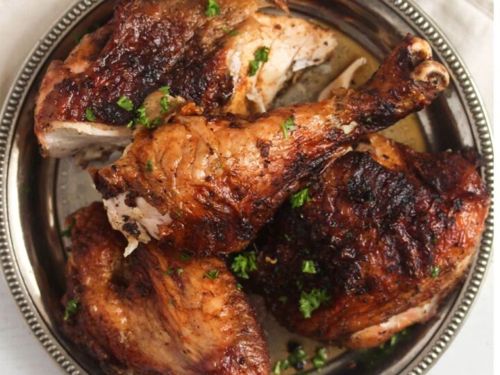 Roasted chicken on a plate with herbs.