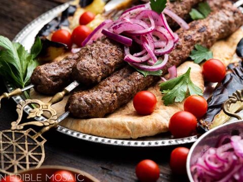 Kebabs with onions and tomatoes on a plate.