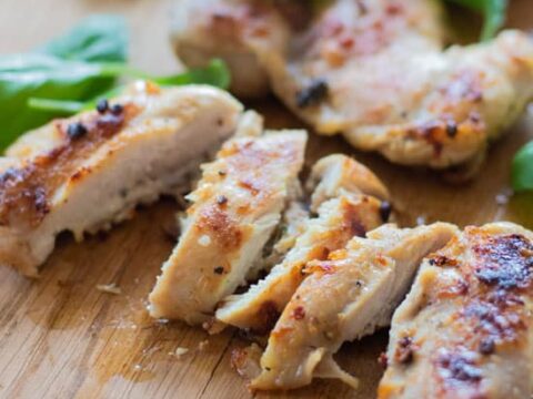 Pieces of meat cut in half with leaves on a wooden surface.