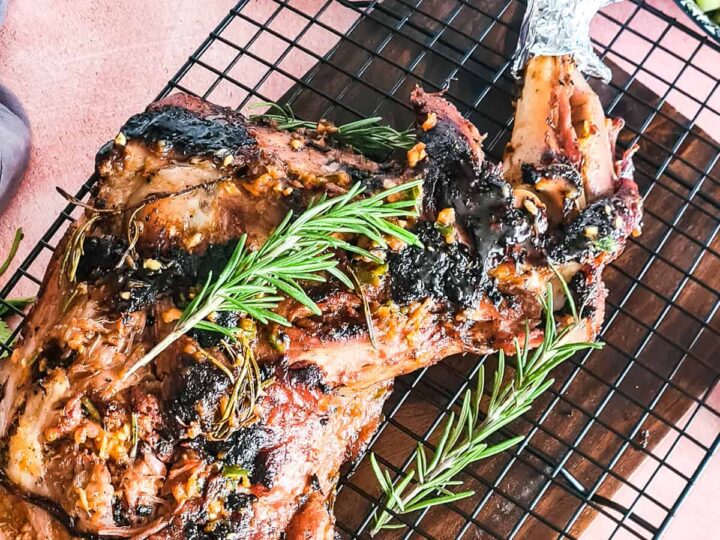 A roasted lamb on a rack with rosemary sprigs.