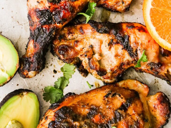 Grilled chicken skewers with orange slices and avocado.