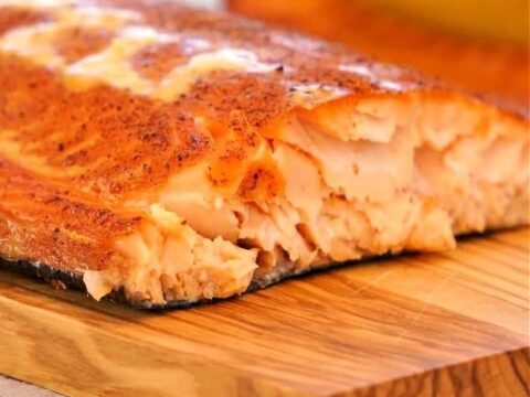 A piece of salmon on a wooden cutting board.