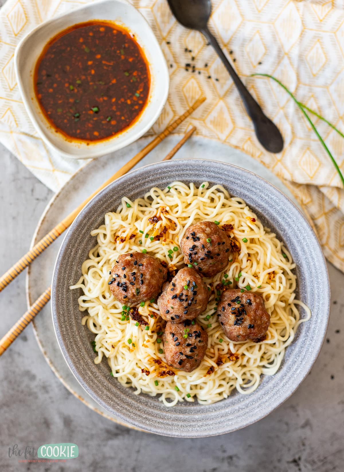 overhead photo of asian pork meatballs on noodles in a gray bowl. 