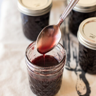 A spoon is being poured into jars of jam.