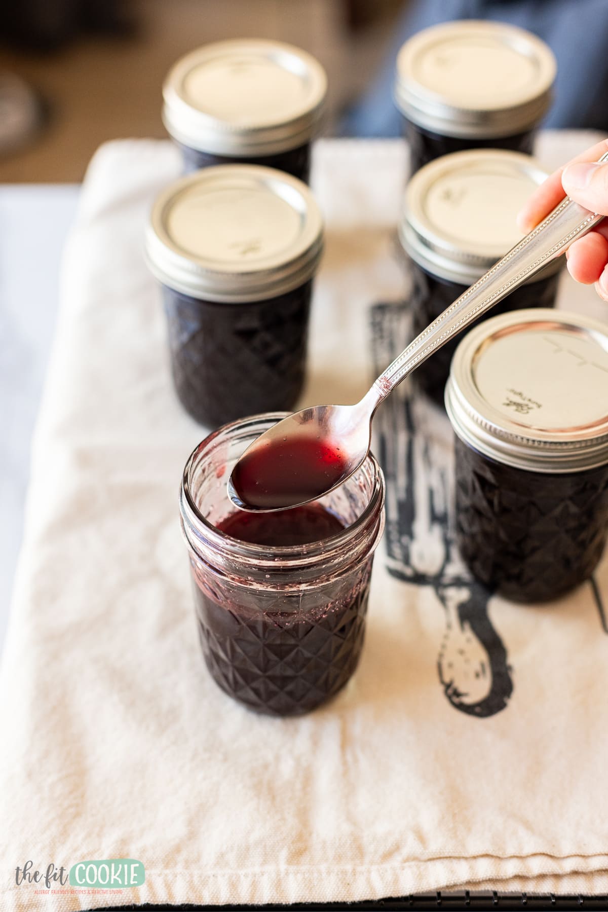 A person pouring Chokecherry Syrup into jars.