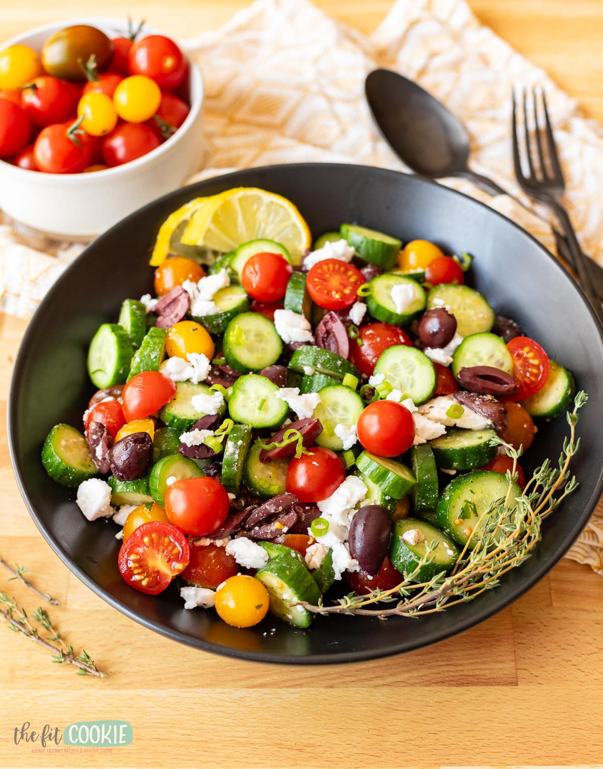 Greek salad with cucumbers, tomatoes, and feta cheese, served in a black bowl.