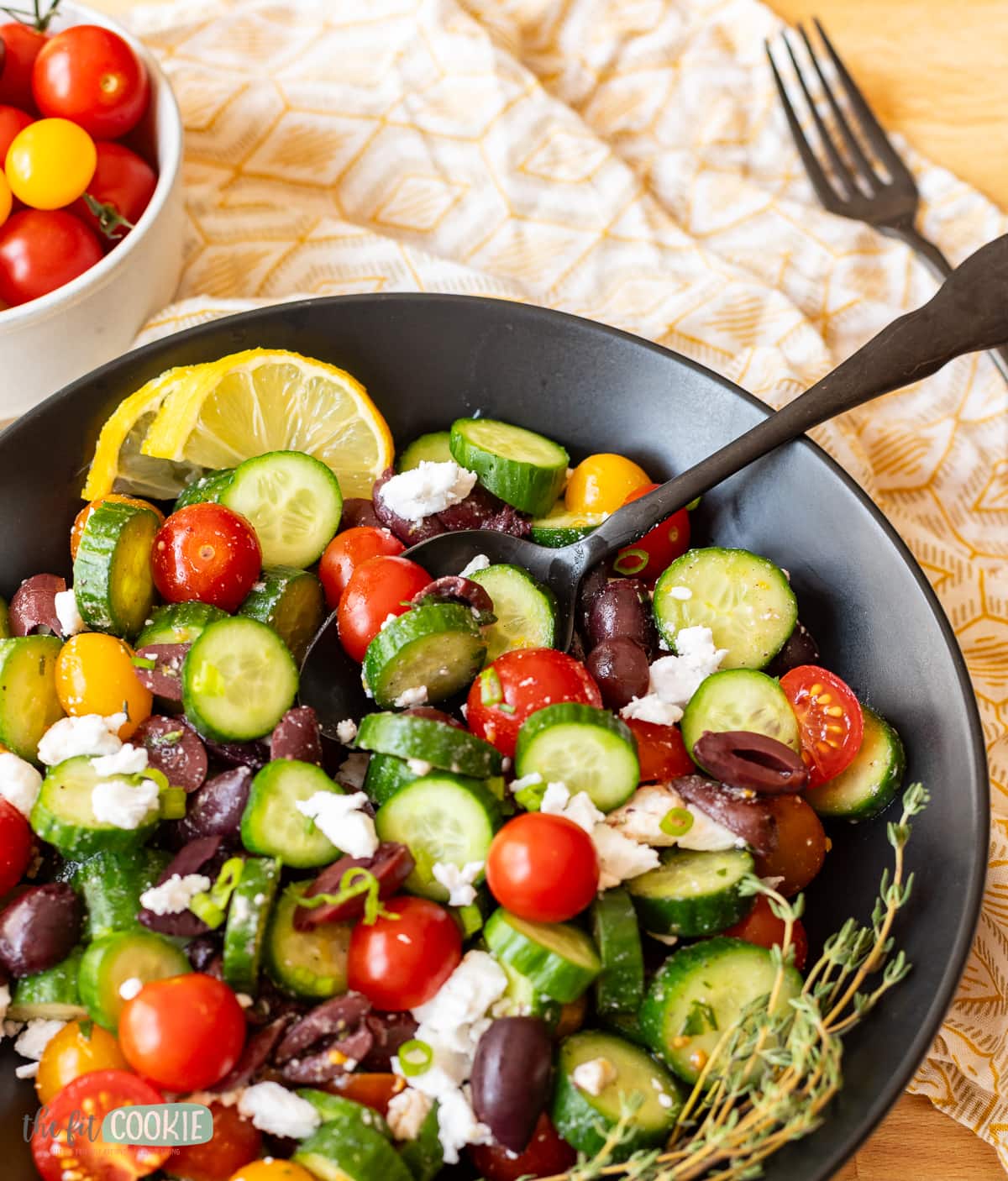 close up of a chopped vegetable salad in a black bowl with a spoon in it. 