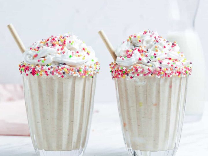 Two cups with whipped cream and sprinkles.