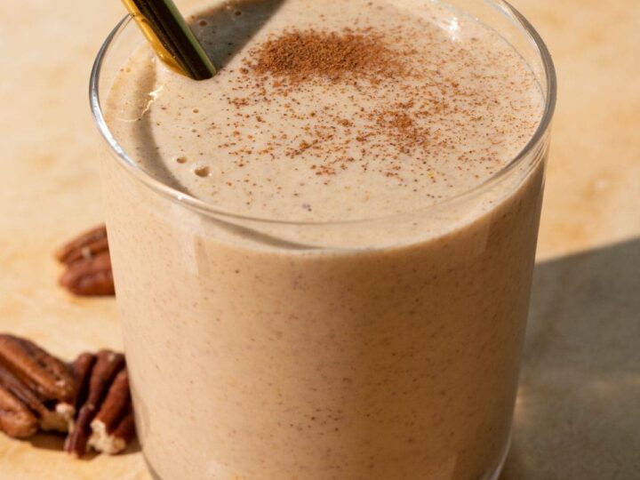 A smoothie with cinnamon and pecans in a glass.