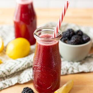 Two bottles of refreshing blackberry lemonade sitting atop a wooden table.