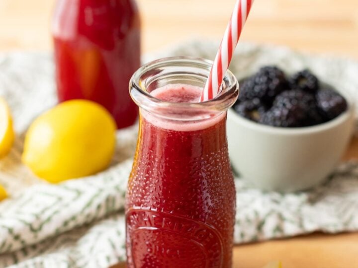Two bottles of refreshing blackberry lemonade sitting atop a wooden table.