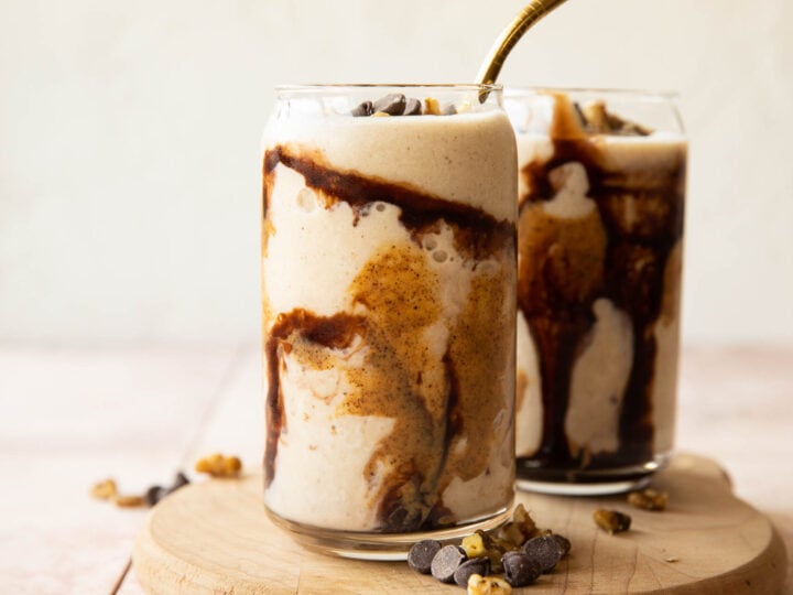 Two glasses filled with ice cream and chocolate syrup.