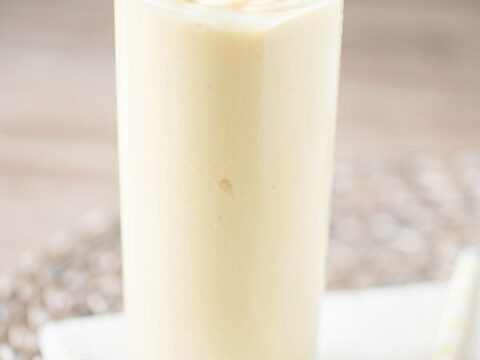 A yellow smoothie with a cherry on top.