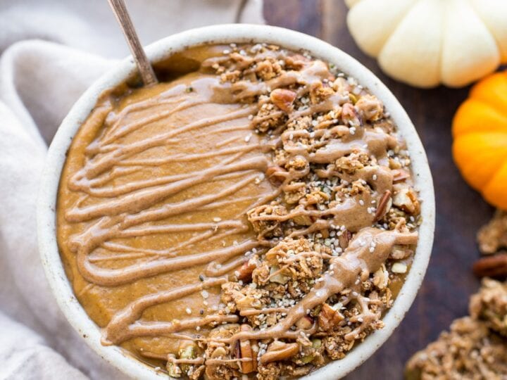 A bowl of pumpkin granola with a spoon and pumpkins.