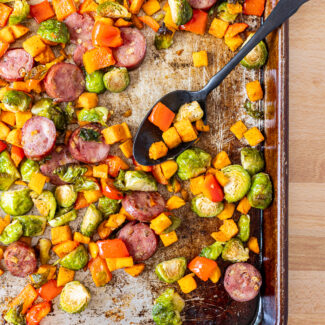 Overhead photo of a baking sheet pan filled with roasted vegetables and sausage.