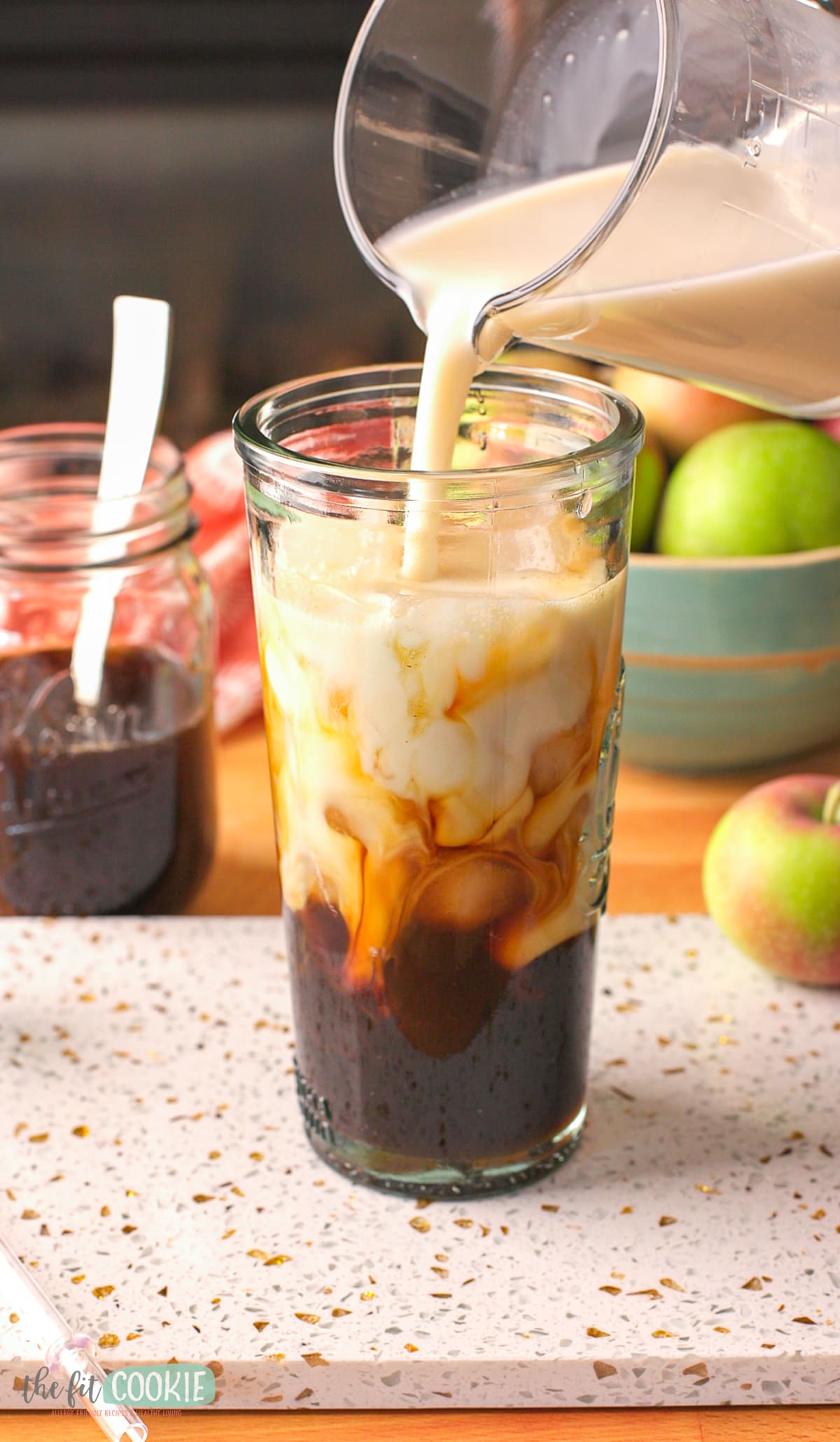 An iced coffee with apple brown sugar syrup being poured into a glass.