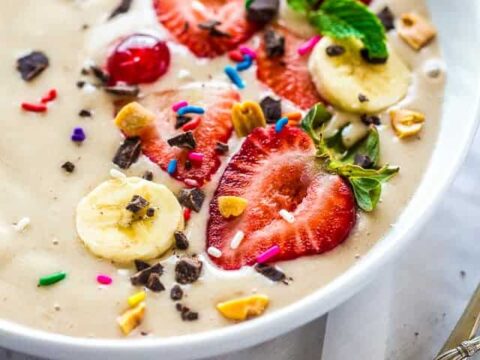 A bowl full of fruit and chocolate in a white bowl.
