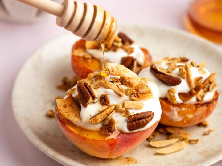 A plate with peaches topped with whipped cream and honey.