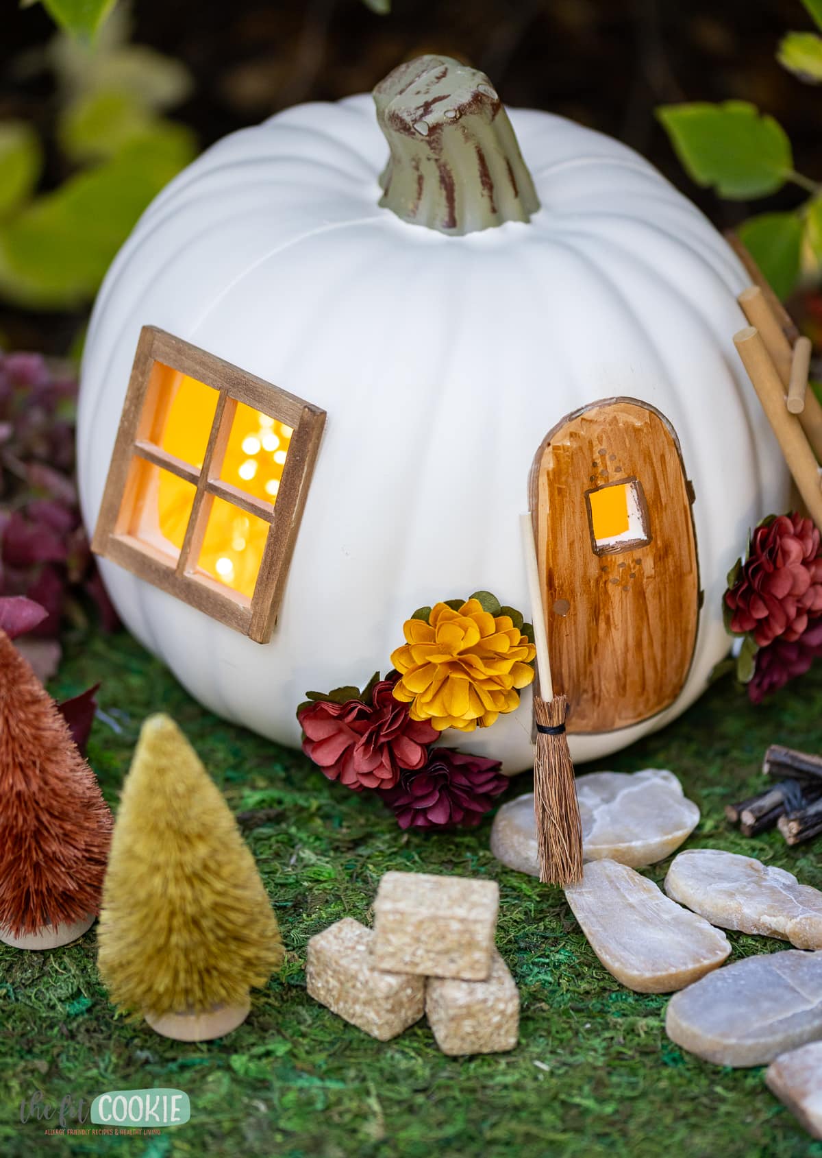 A fairy house pumpkin nestled in a grassy area.