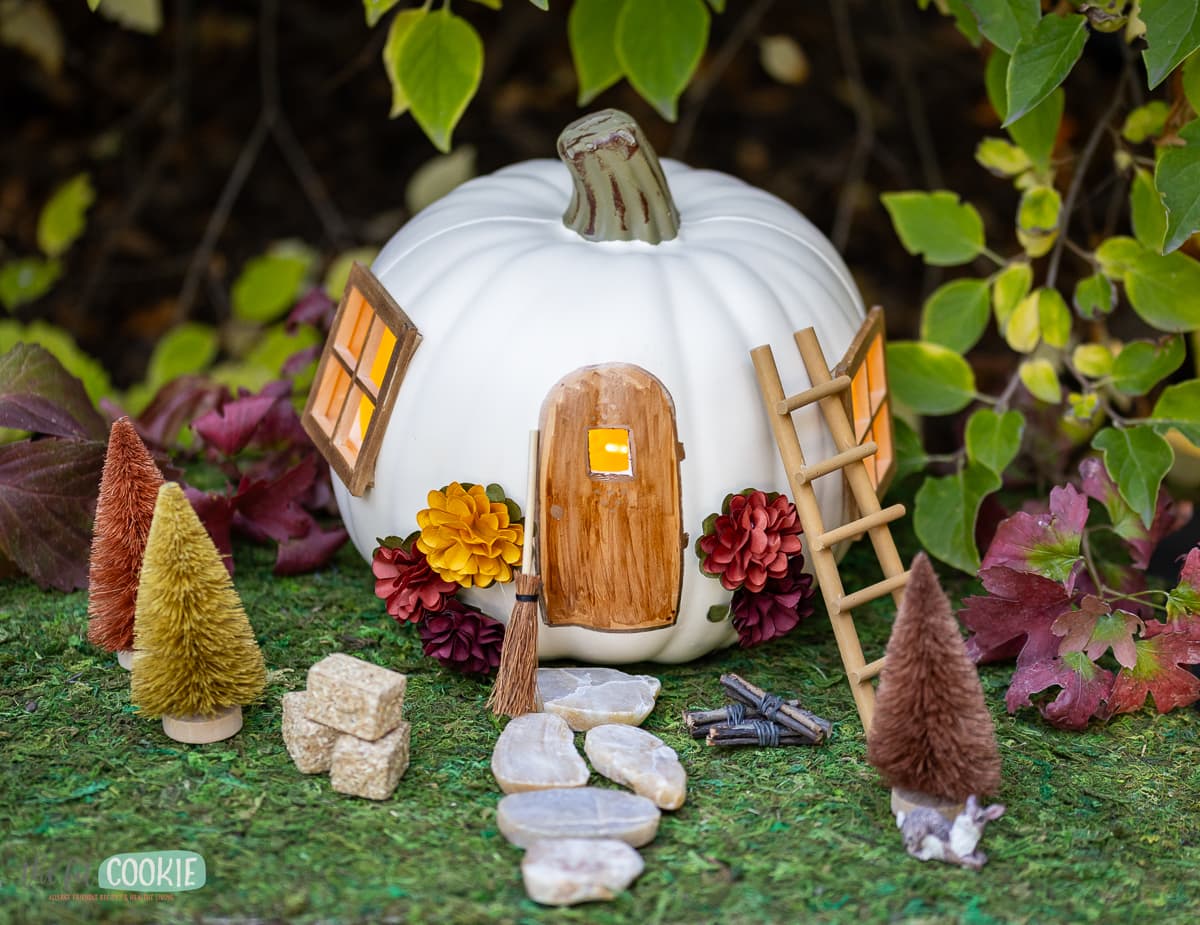 a pumpkin fairy house that is made with a white craft pumpkin. 