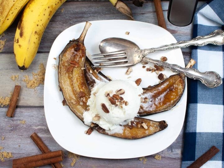 A plate with bananas, ice cream and cinnamon sticks.