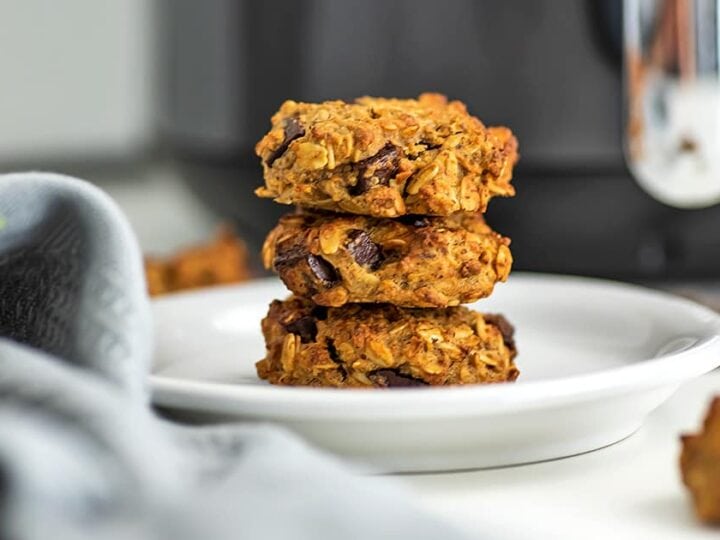 A stack of oatmeal cookies on a plate in front of an instant pot.