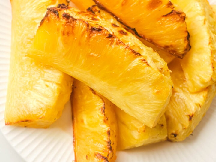 Grilled pineapple slices on a white plate.