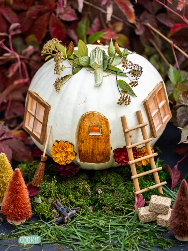 A pumpkin with a fairy house on top of it.