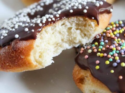 Donuts with chocolate icing and sprinkles on a plate.